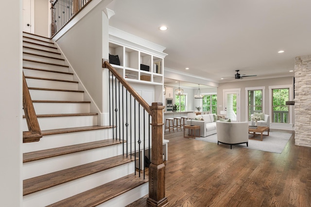 stairway with wood-type flooring, crown molding, and ceiling fan