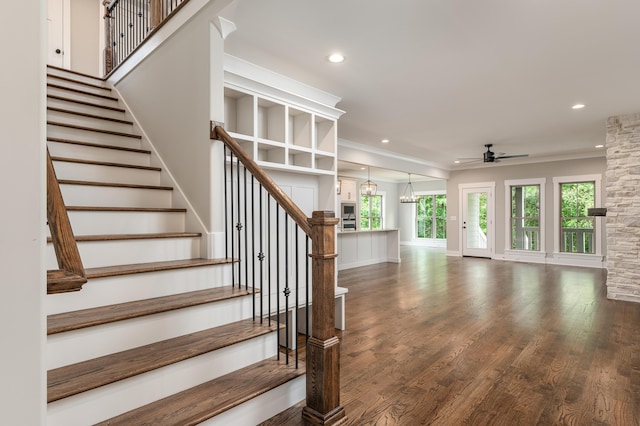 stairs with crown molding, hardwood / wood-style flooring, and ceiling fan