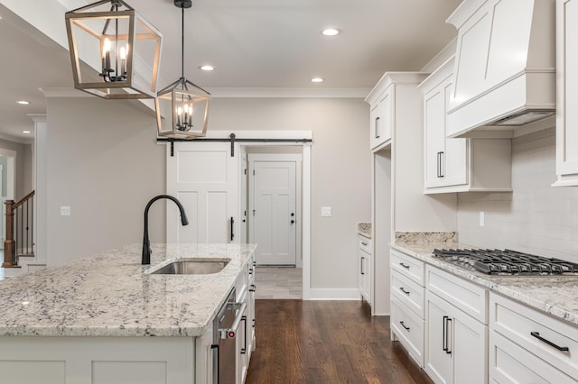 kitchen with dark hardwood / wood-style floors, an island with sink, sink, a barn door, and custom exhaust hood