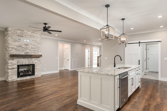 kitchen featuring a barn door, an island with sink, sink, dark wood-type flooring, and white cabinets