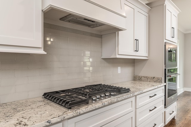 kitchen with dark hardwood / wood-style floors, custom range hood, tasteful backsplash, stainless steel appliances, and white cabinetry