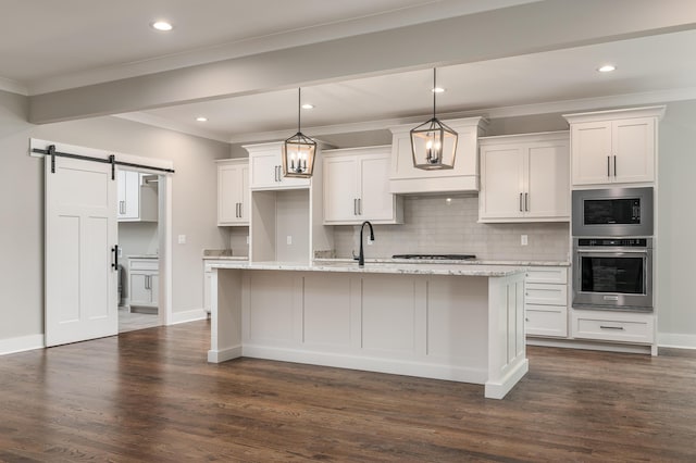 kitchen featuring white cabinetry, a barn door, dark hardwood / wood-style flooring, and a kitchen island with sink