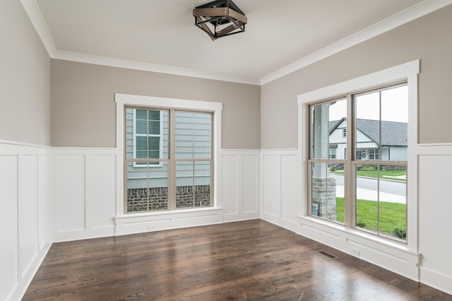 empty room with dark wood-style floors, a decorative wall, visible vents, and ornamental molding