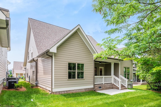 rear view of property with central AC, a yard, and covered porch