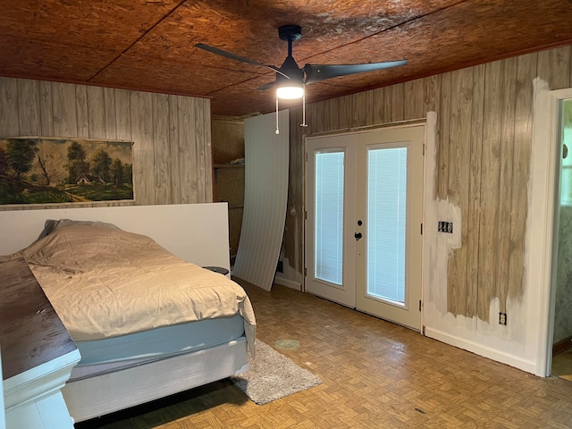 bedroom with french doors, parquet floors, ceiling fan, and wooden walls