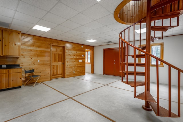 interior space featuring wooden walls and a drop ceiling