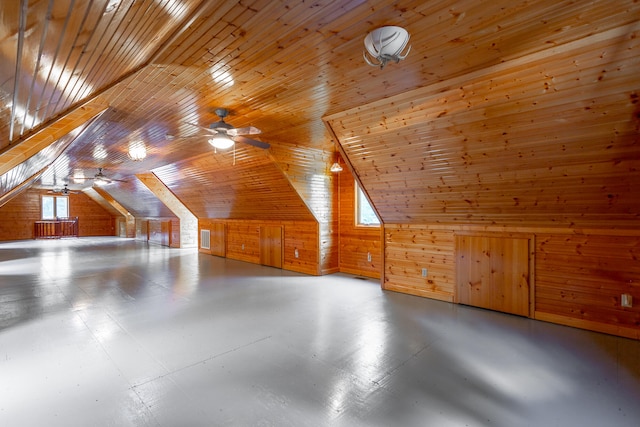 bonus room with vaulted ceiling, wood walls, concrete flooring, wood ceiling, and ceiling fan