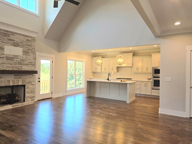 kitchen featuring pendant lighting, an island with sink, ceiling fan, and dark wood-type flooring