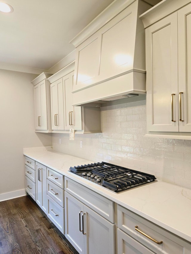 kitchen featuring stainless steel gas stovetop, premium range hood, light stone countertops, and dark hardwood / wood-style floors