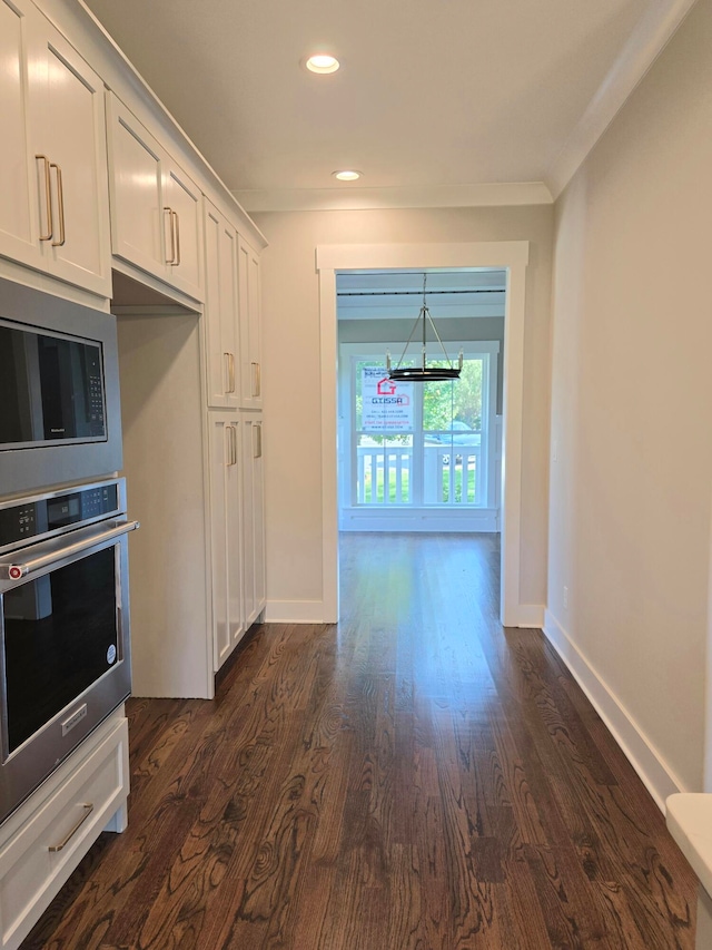 kitchen with a notable chandelier, dark hardwood / wood-style flooring, hanging light fixtures, appliances with stainless steel finishes, and white cabinets