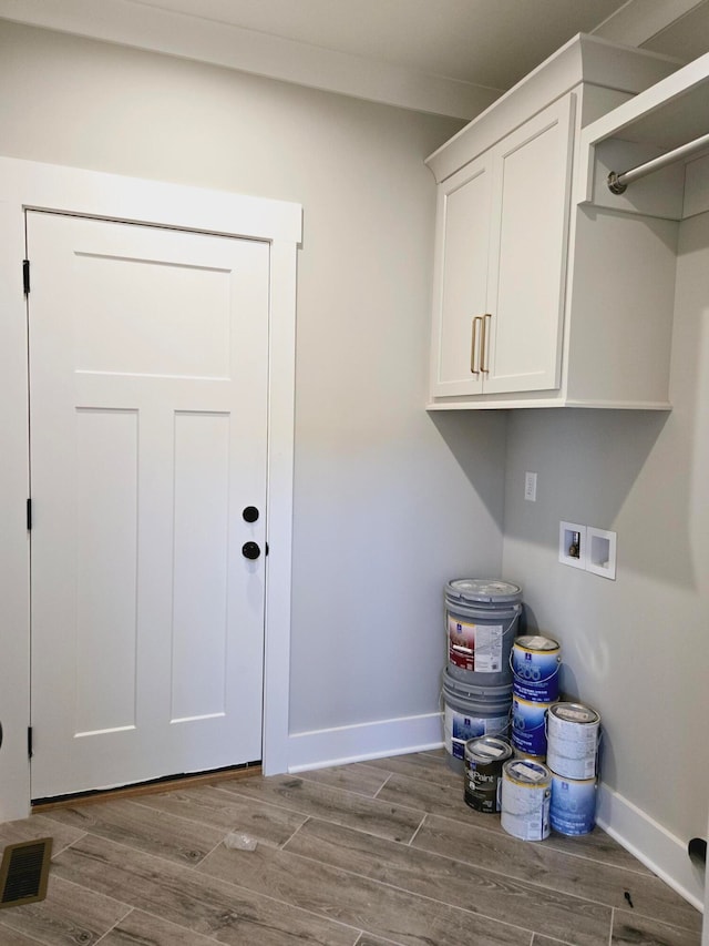 laundry area featuring light wood-type flooring, washer hookup, and cabinets