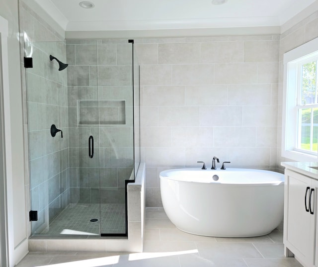 bathroom featuring tile patterned flooring, crown molding, vanity, independent shower and bath, and tile walls