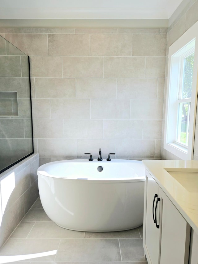 bathroom with a bath, tile walls, tile patterned flooring, and vanity