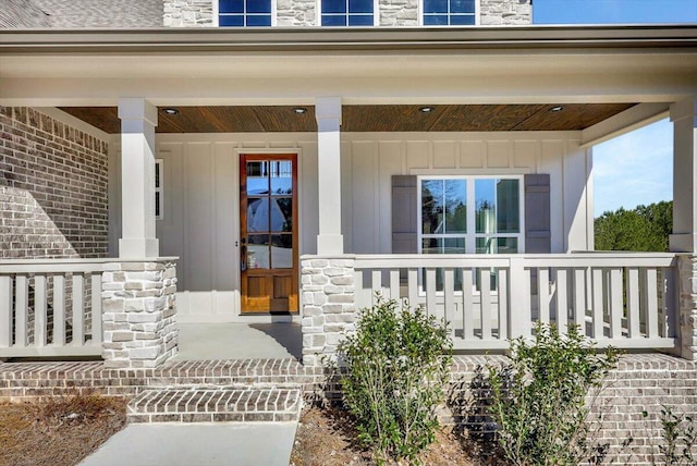 property entrance featuring stone siding, a porch, and board and batten siding