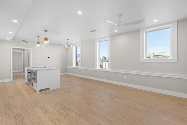 interior space featuring ceiling fan with notable chandelier and light wood-type flooring