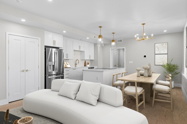 living room with sink, an inviting chandelier, and light wood-type flooring