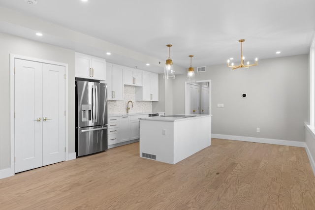 kitchen featuring stainless steel fridge with ice dispenser, a center island, white cabinetry, and hanging light fixtures