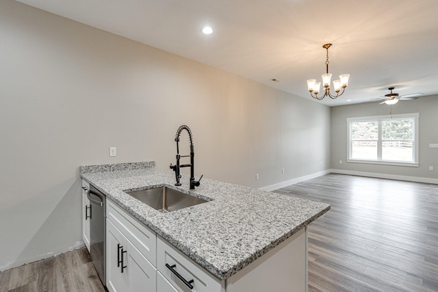 kitchen with dishwasher, sink, white cabinets, hanging light fixtures, and light stone counters