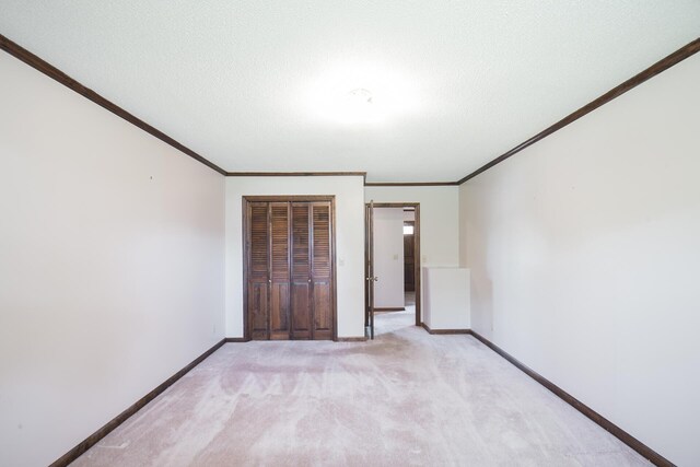 unfurnished bedroom featuring ornamental molding, a textured ceiling, light colored carpet, and a closet