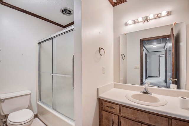 full bathroom featuring enclosed tub / shower combo, a textured ceiling, toilet, ornamental molding, and vanity