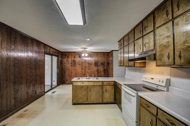 kitchen with sink, electric range, ceiling fan, wooden walls, and crown molding