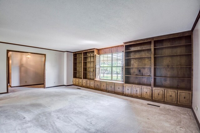 unfurnished living room featuring ornamental molding, a textured ceiling, and light colored carpet