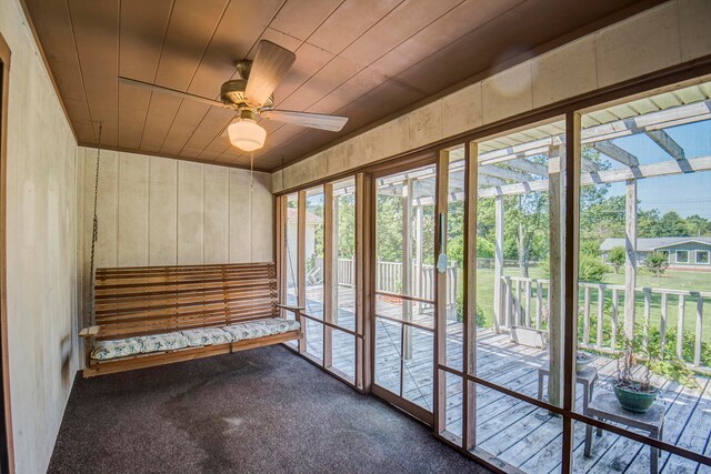 unfurnished sunroom with wood ceiling and ceiling fan