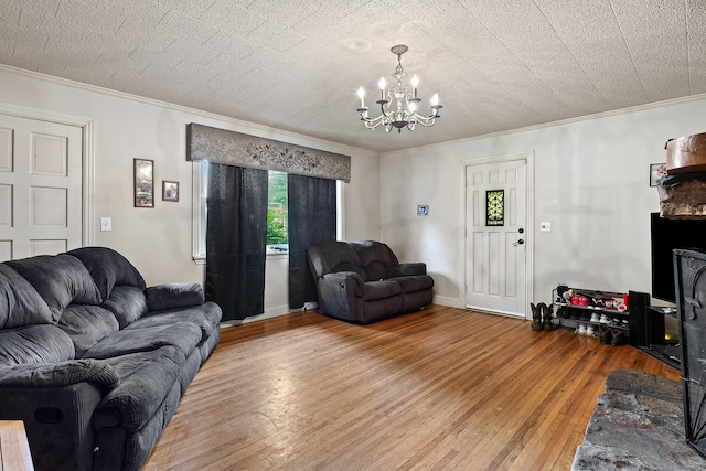 living room with hardwood / wood-style floors, an inviting chandelier, a textured ceiling, and ornamental molding