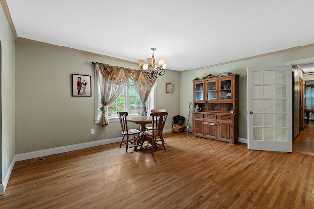 dining room with crown molding, wood-type flooring, and a notable chandelier