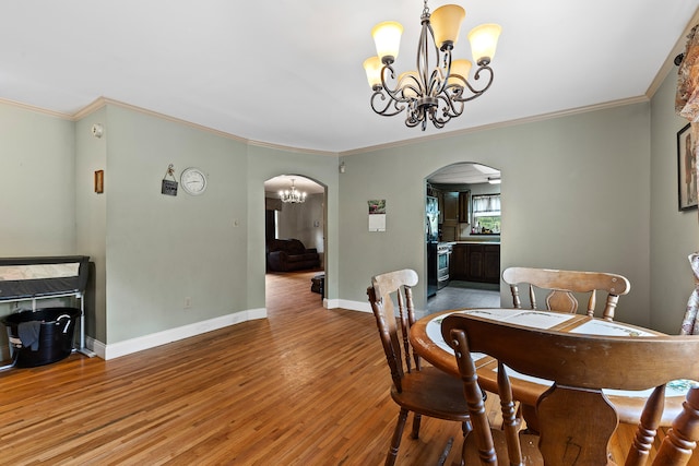 dining space featuring crown molding, wood-type flooring, and a chandelier