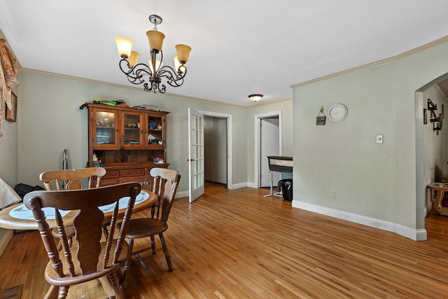 dining area featuring crown molding, hardwood / wood-style floors, and an inviting chandelier