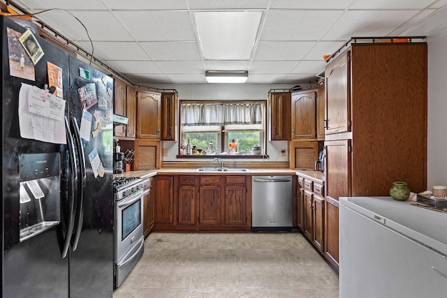 kitchen with stainless steel appliances, sink, and a drop ceiling