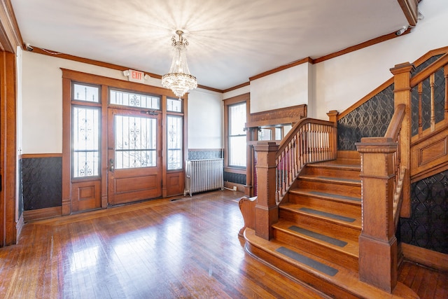 foyer entrance featuring crown molding, dark wood-type flooring, a notable chandelier, and radiator heating unit