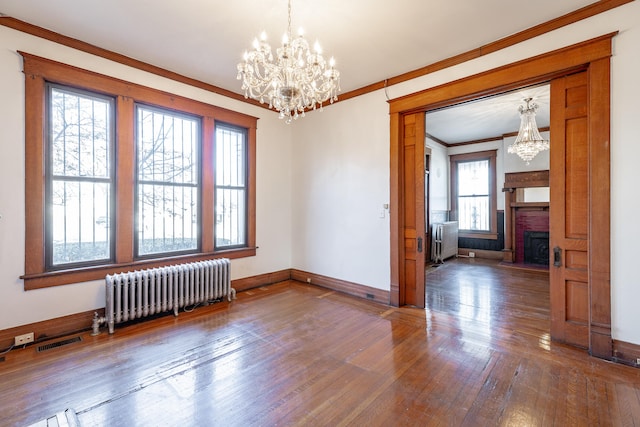 spare room featuring radiator, a healthy amount of sunlight, and an inviting chandelier