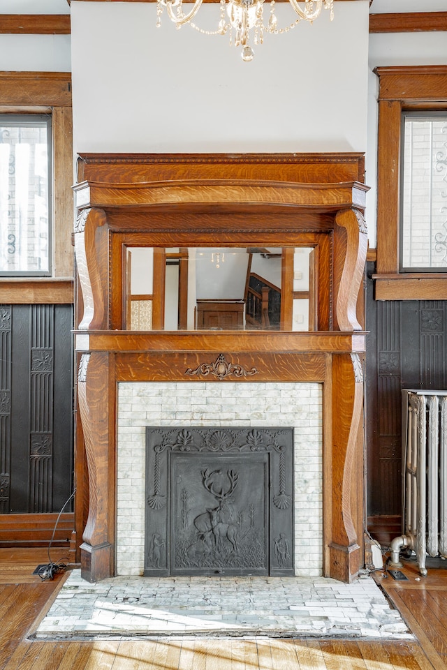 details with an inviting chandelier, hardwood / wood-style flooring, and a fireplace