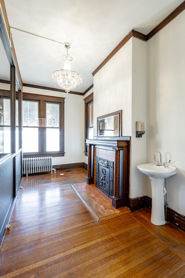 unfurnished living room with a chandelier, dark hardwood / wood-style floors, radiator heating unit, and crown molding