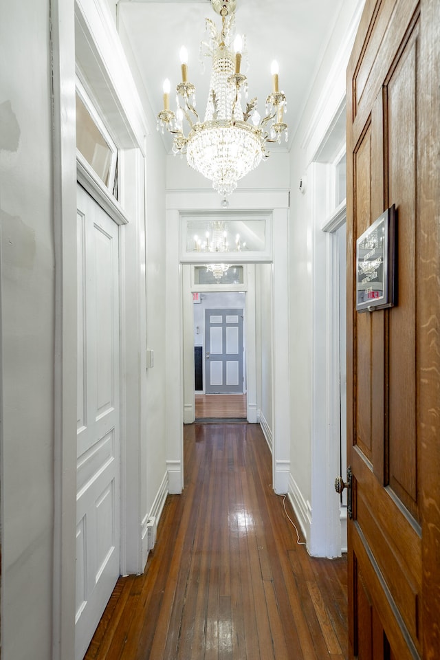 corridor featuring dark hardwood / wood-style flooring, a chandelier, and crown molding