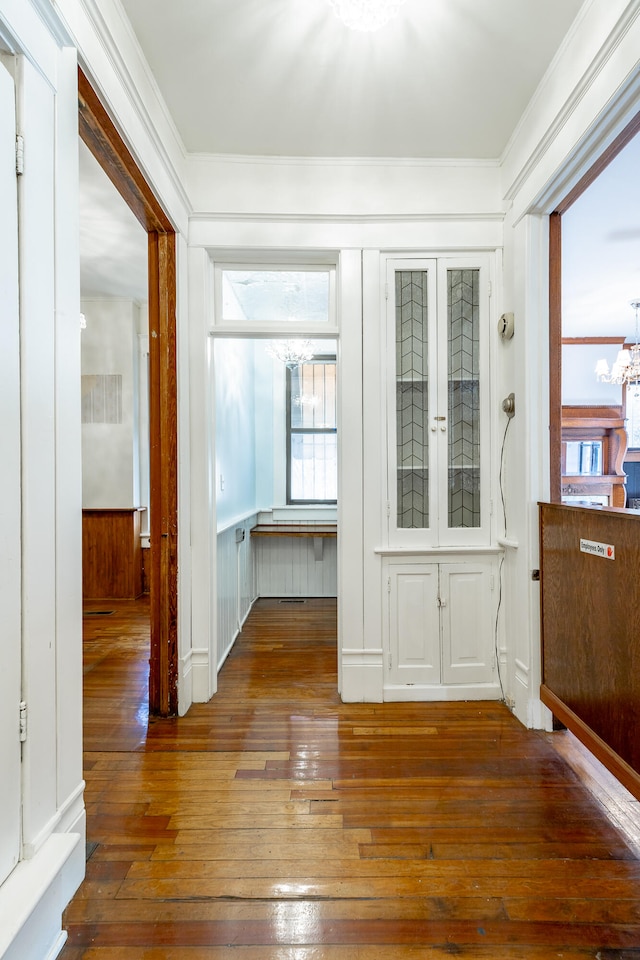 interior space with ornamental molding, hardwood / wood-style flooring, wood walls, and a notable chandelier