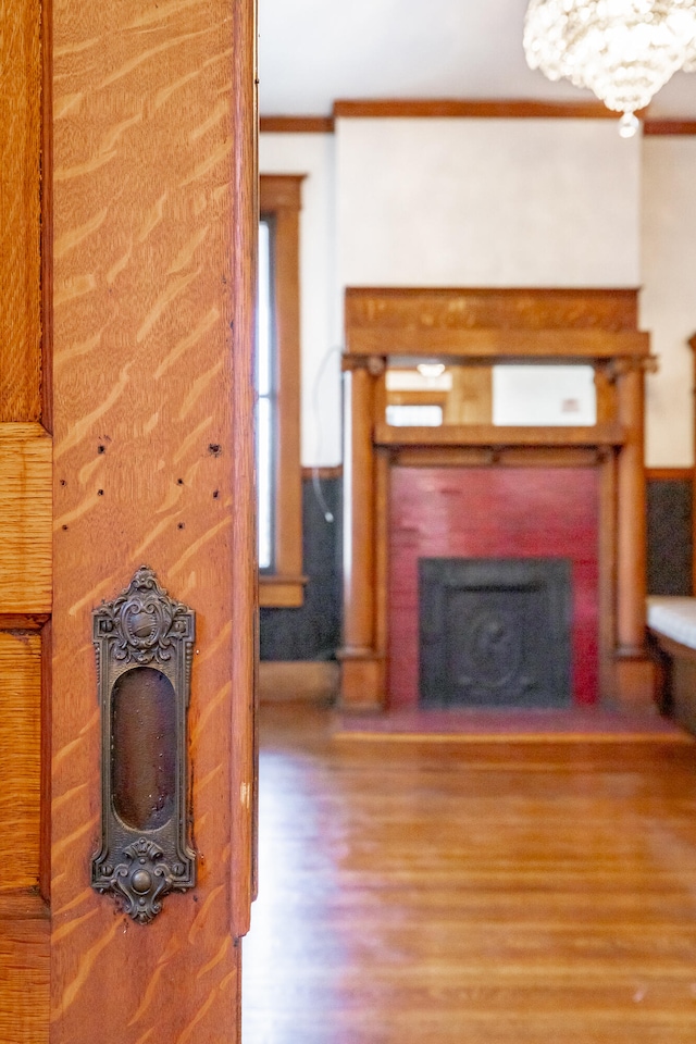 unfurnished living room featuring wood-type flooring, a fireplace, and ornamental molding