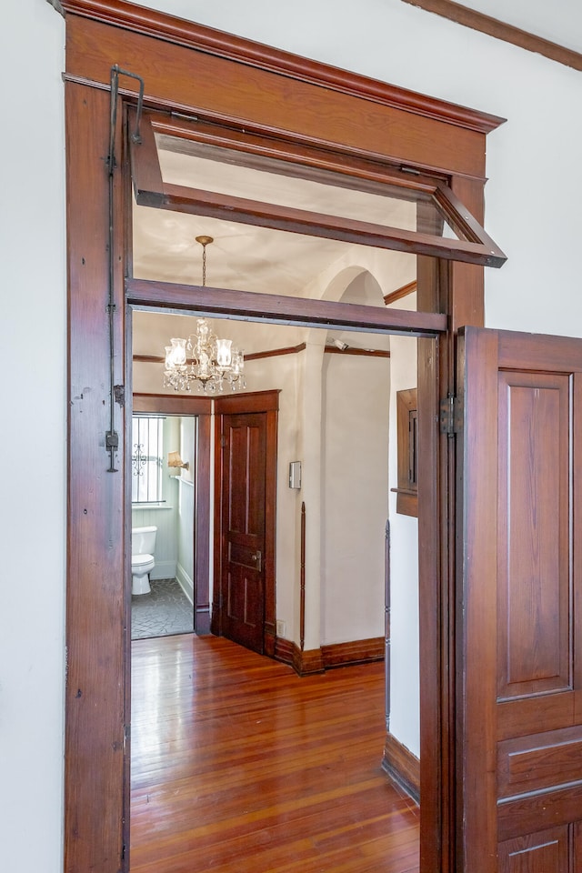 hall with dark hardwood / wood-style floors and a notable chandelier