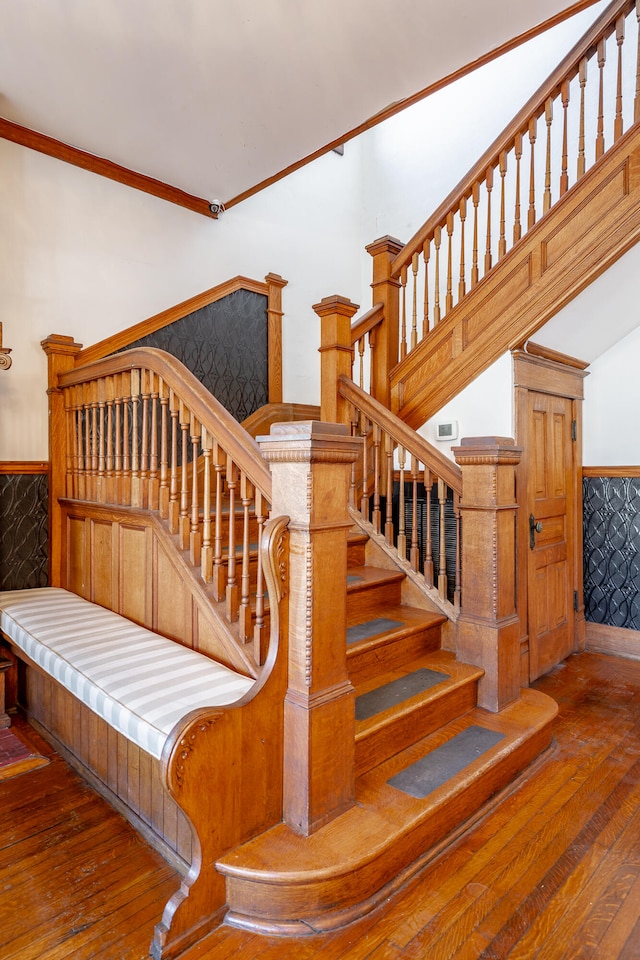 stairway with hardwood / wood-style floors and crown molding