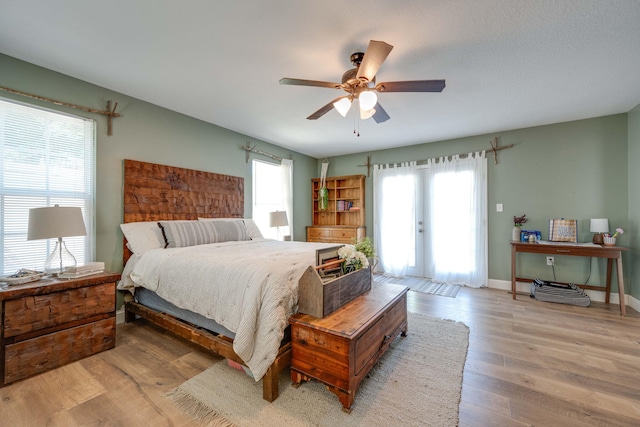 bedroom featuring multiple windows, ceiling fan, light hardwood / wood-style floors, and french doors