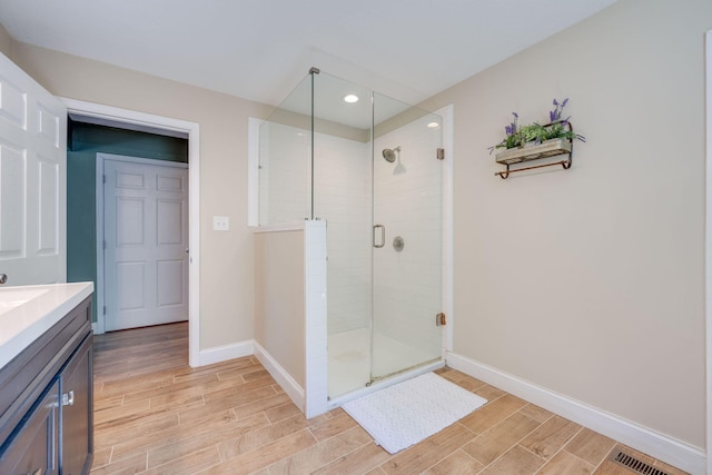 bathroom featuring a shower with door and vanity