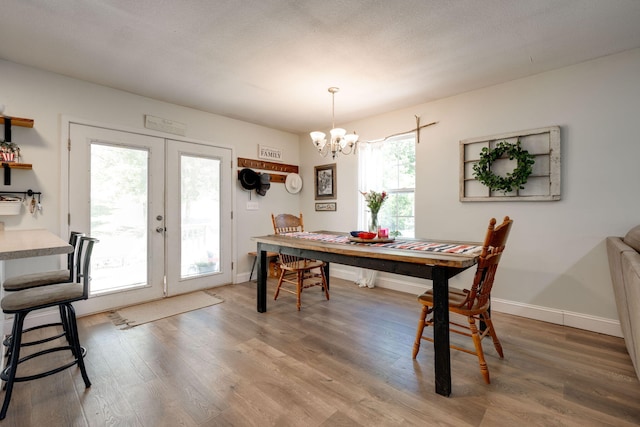 dining room featuring a textured ceiling, a healthy amount of sunlight, a notable chandelier, and wood-type flooring