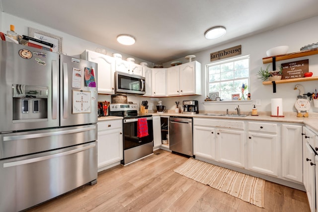 kitchen featuring white cabinets, appliances with stainless steel finishes, light hardwood / wood-style floors, and sink