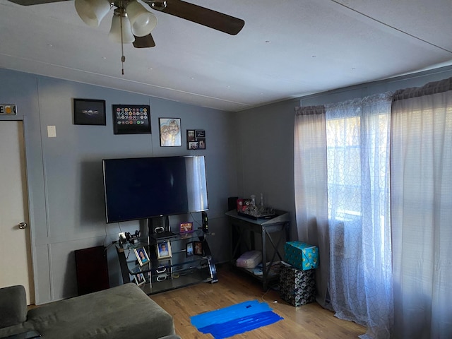 living room with ceiling fan, wood-type flooring, and vaulted ceiling