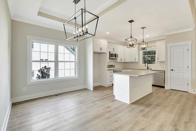 kitchen with decorative light fixtures, a center island, stainless steel appliances, white cabinetry, and plenty of natural light