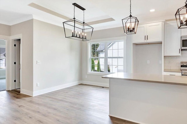 kitchen with white cabinetry, wood-type flooring, and decorative light fixtures