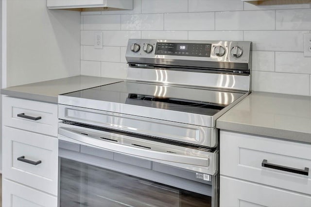 kitchen with tasteful backsplash, stainless steel range with electric cooktop, and white cabinets