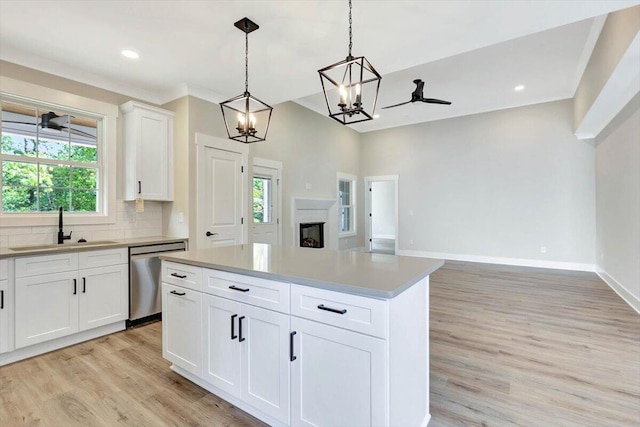 kitchen featuring hanging light fixtures, a healthy amount of sunlight, ceiling fan with notable chandelier, white cabinetry, and stainless steel dishwasher